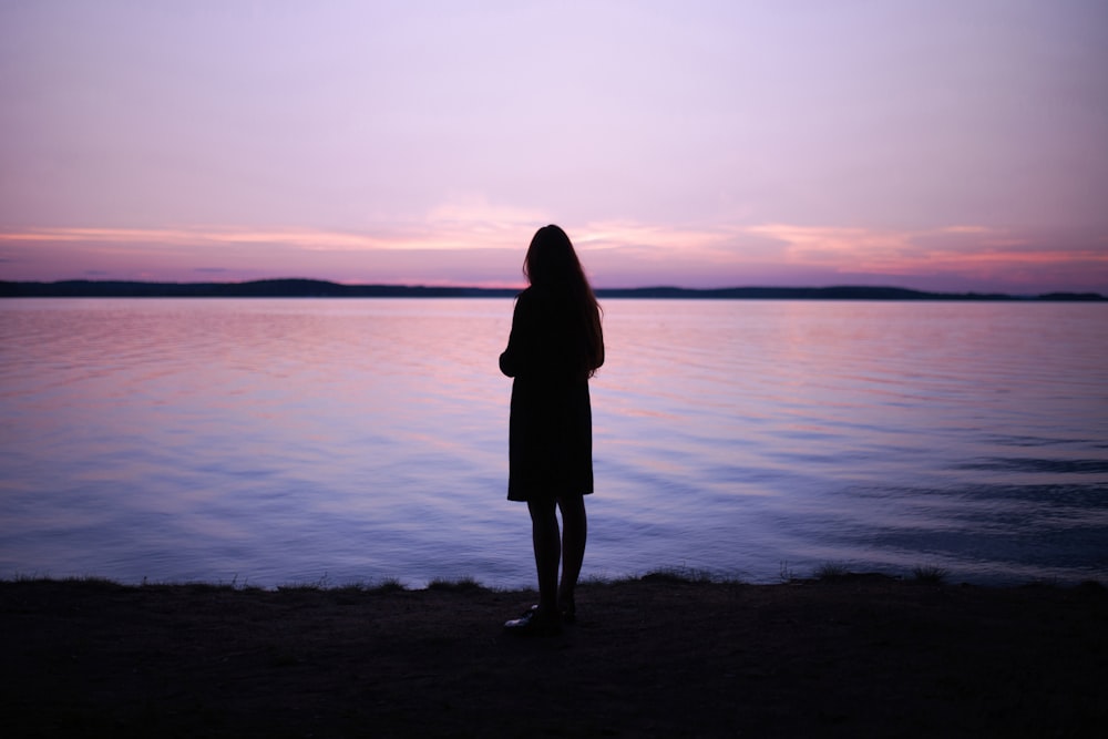 woman standing near body of water during golden hour