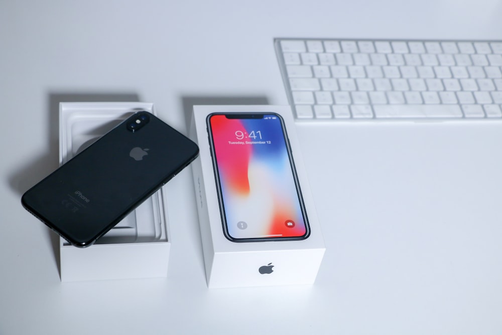 space gray iPhone X on table beside keyboard