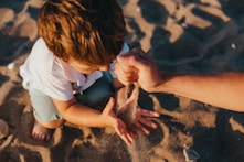 person pouring sand into boys hands