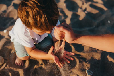 Close-up of a child’s hands shaping sand in the outdoor sand pit on a sunny day.