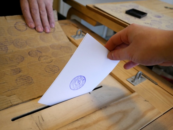 Close-up of hands exchanging ballots during a monitored election process.