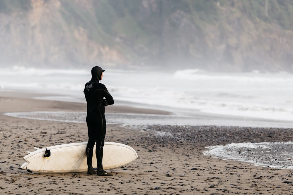 man standing on shoreline with surfboard