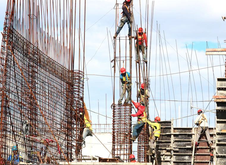 Workers tying reinforcement cages on concrete columns at height