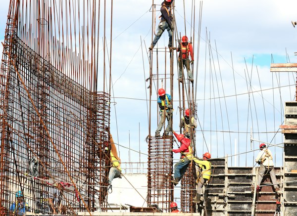 Trabajadores con casco armando varilla en una obra, escenario del marketing para empresas de construcción industrial