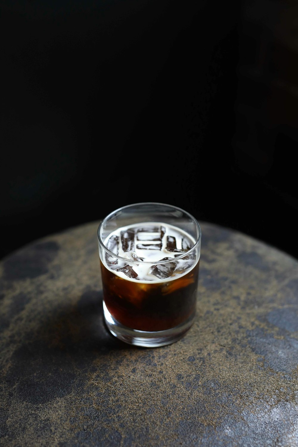 glass of iced coffee placed on brown stone