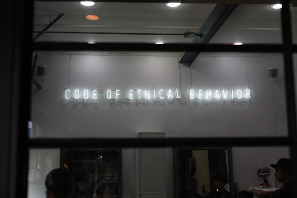 a neon side reading "code of ethical behavior" in a darkened room