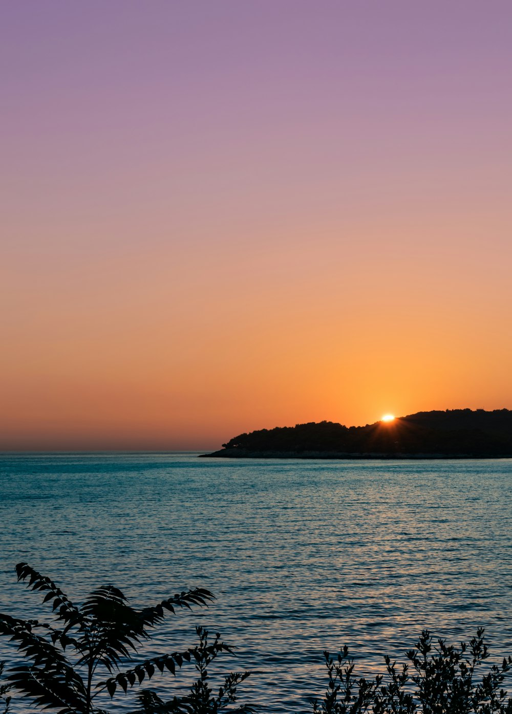 sea with silhouette of island during golden hour