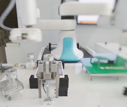 A mechanical laboratory setup featuring a robotic arm and several mechanical components, including precision instruments and metallic structures. The setup appears to be for industrial automation or testing purposes, with a clean and organized environment.