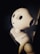 A humanoid robot with large, round eyes and a smooth, white surface is shown. The lighting is dim and casts shadows, highlighting the robot’s sleek and futuristic design.