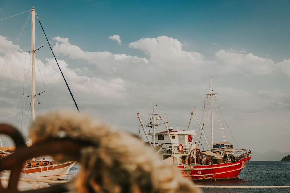 red and white fishing vessel on sea under cloudy sky