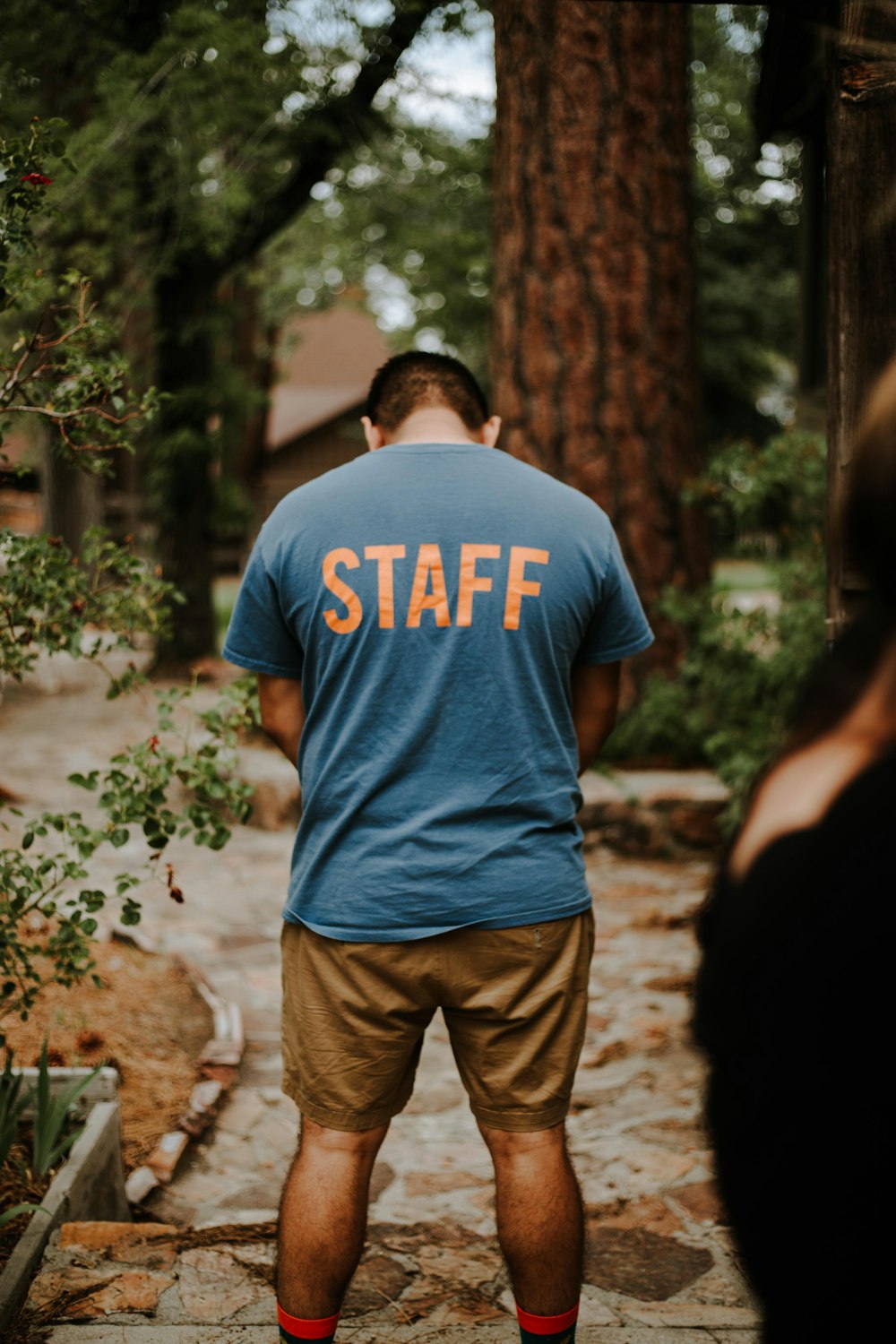 standing man wearing staff t-shirt near tree
