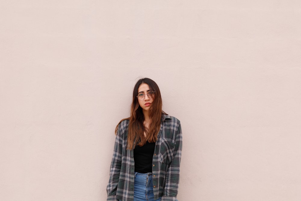 woman wearing gray dress shirt leaning white wall