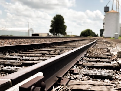 Close-up of wooden railroad ties stacked neatly beside railway tracks under a clear sky