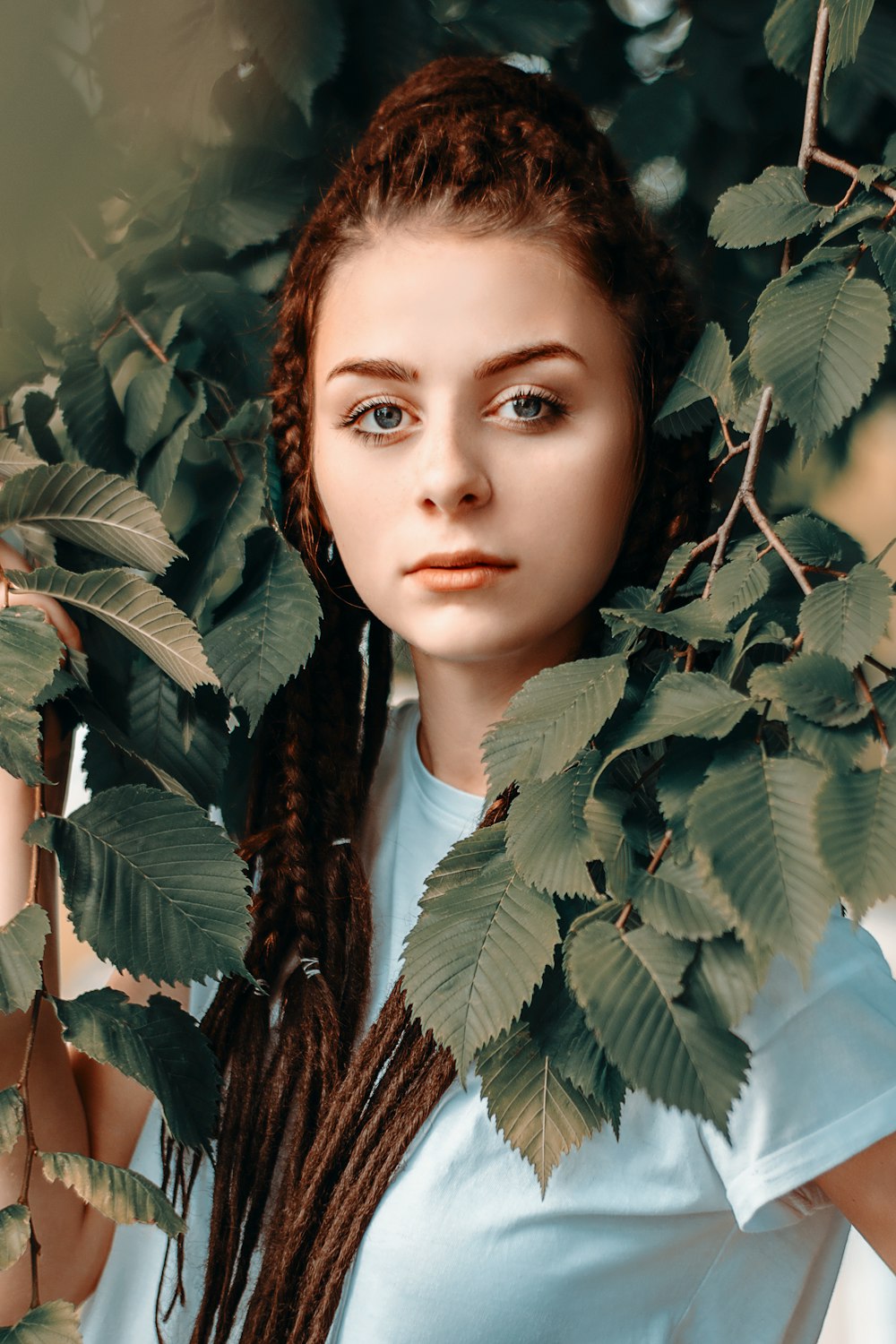 a woman with long braids standing under a tree