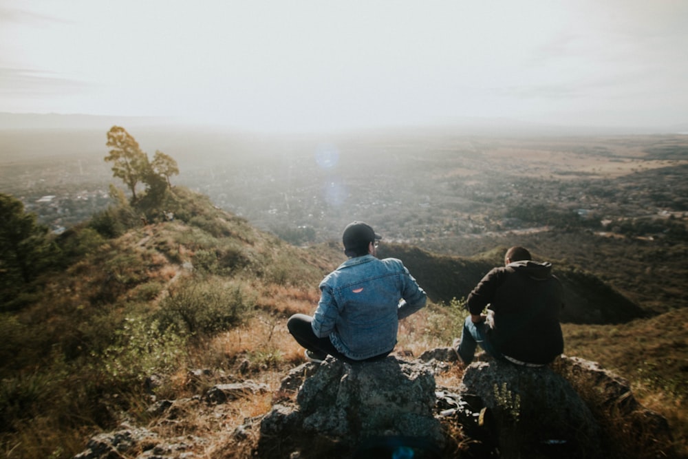 two person sitting on rock