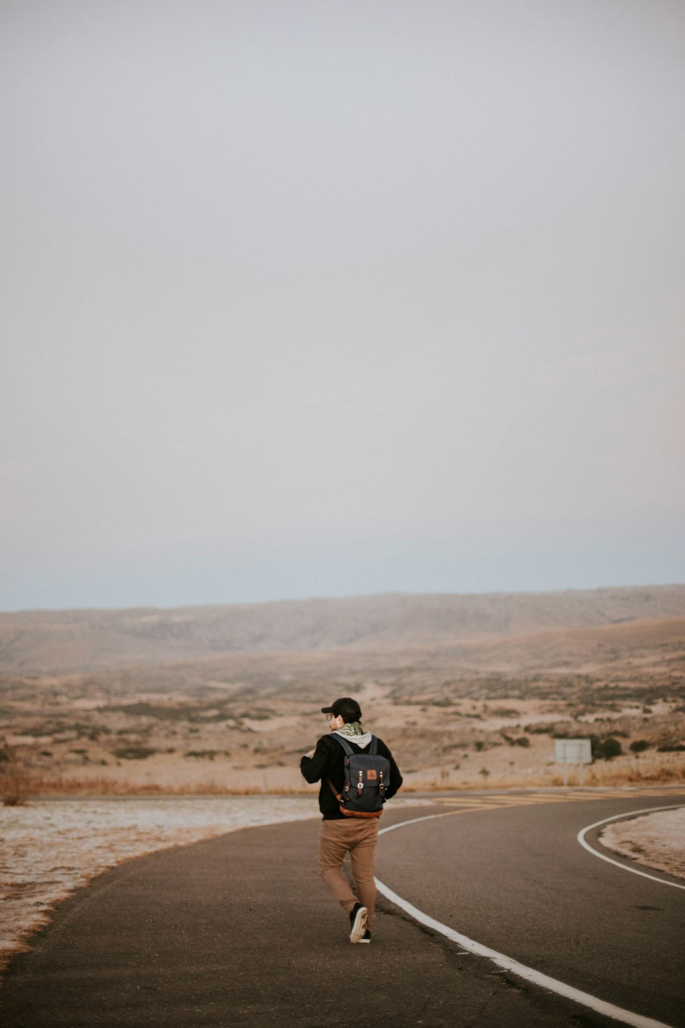 man walking in middle of asphalt road