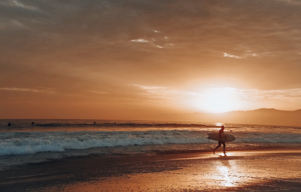 man carrying surfboard at the beach