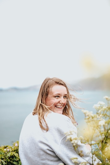 woman sitting on garden near body of water