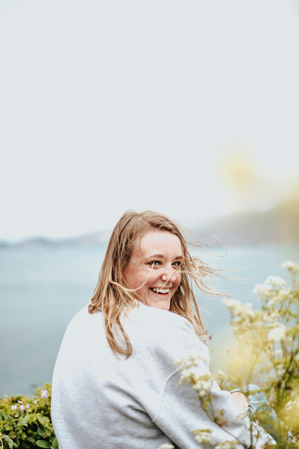 woman sitting on garden near body of water