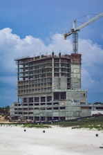 An engineer reviewing structural blueprints on a construction site with a partially built commercial building in the background.