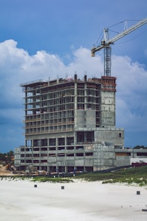 A construction supervisor reviewing blueprints on site with a partially built commercial building in the background.