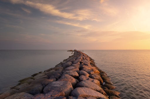 scenery of gray rocks pier on body of water during daytine