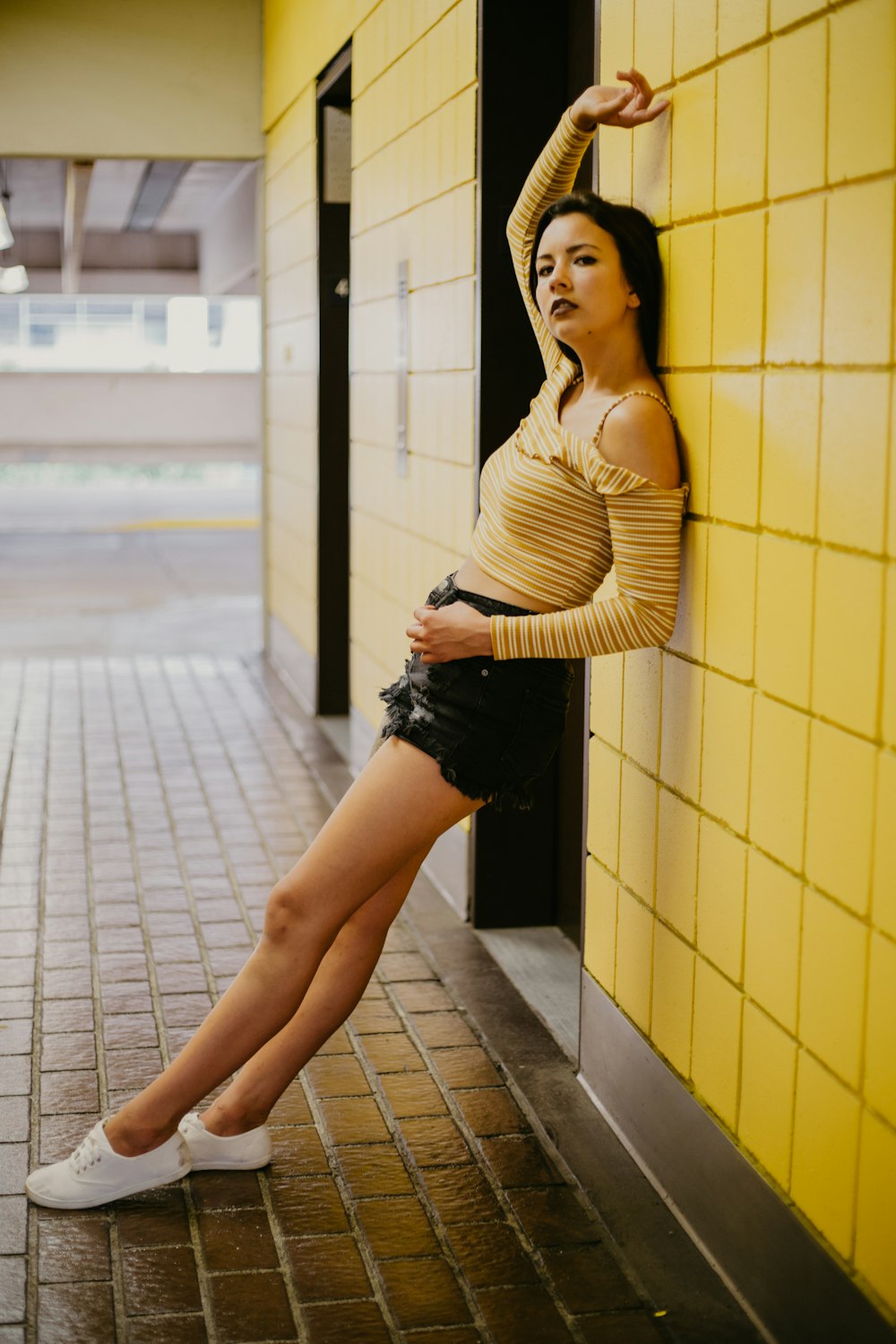 woman standing behind yellow wall