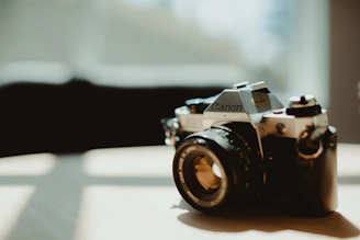 A stylish camera resting on a vintage wooden table with soft natural light.