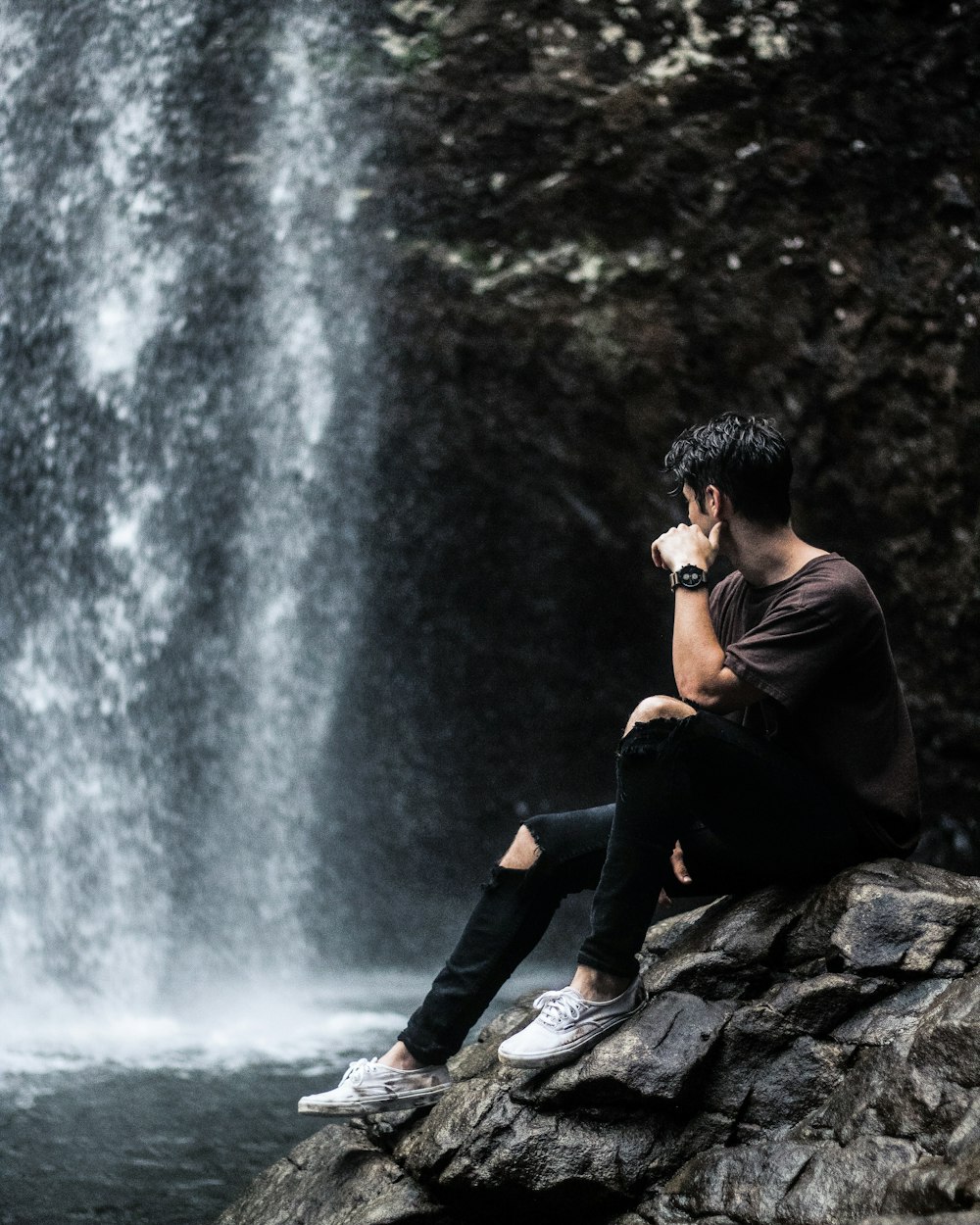 homme assis près des chutes d’eau