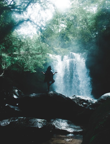 woman facing waterfall doing yoga