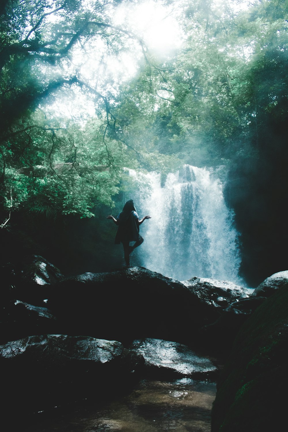 woman facing waterfall doing yoga