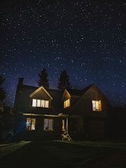 Night view of a villa illuminated with soft outdoor lighting and a starry sky.