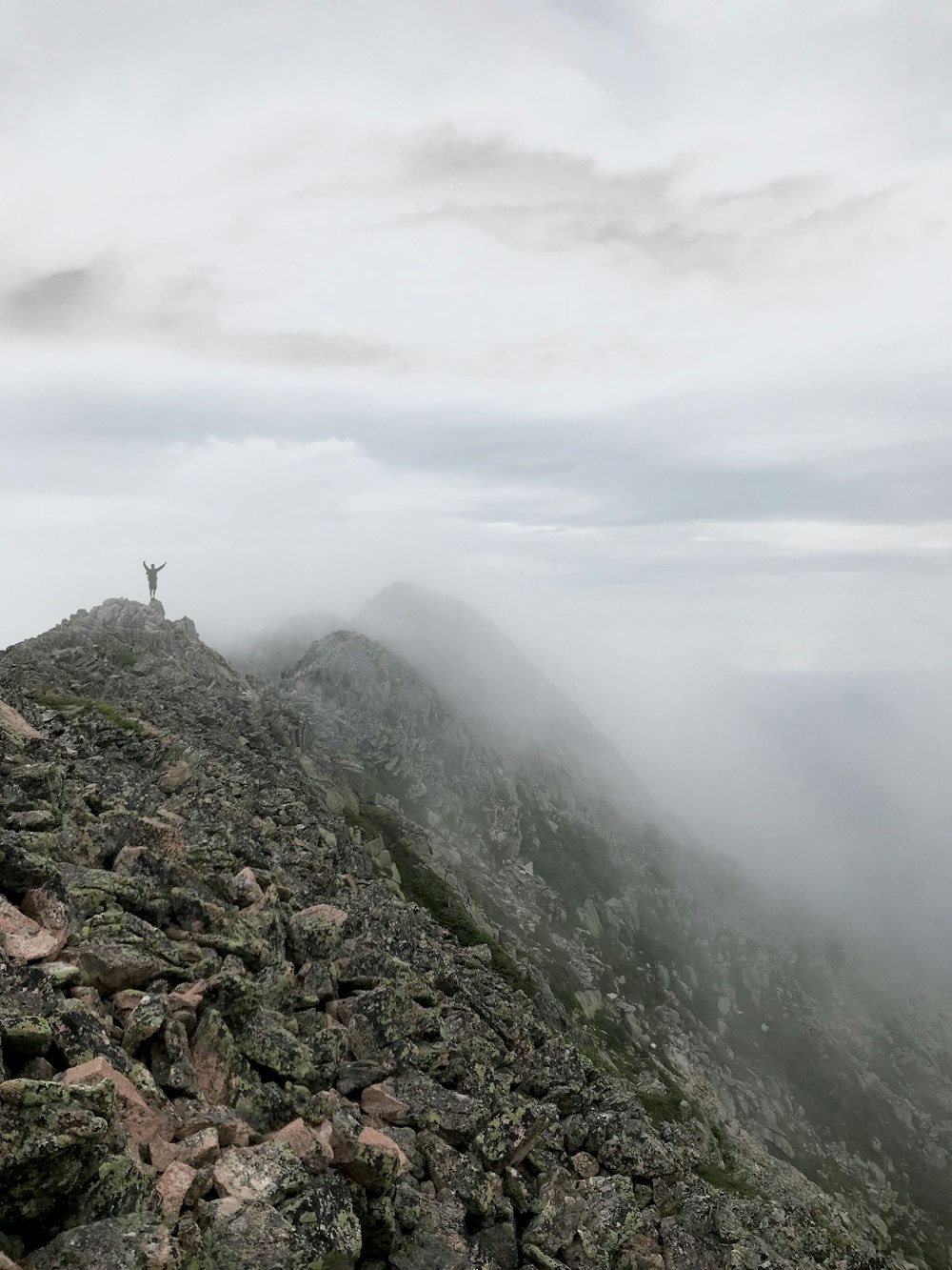 Persona de pie en la cumbre de la montaña con niebla