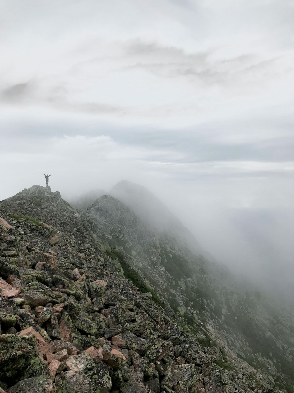 person standing on mountain summit with fog