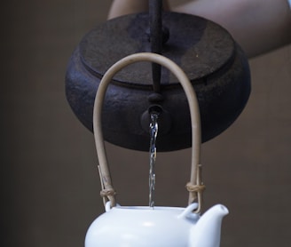 person pouring water on ceramic teapot