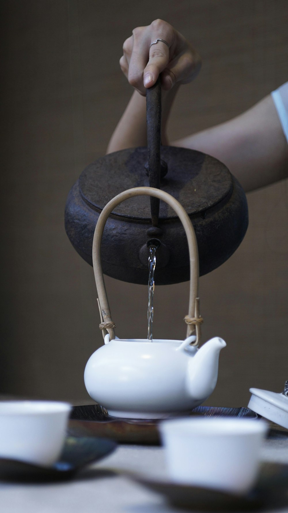 person pouring water on ceramic teapot