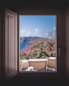 opened window showing outdoor lounger and pink flowers with mountain background