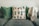 A comfortable sofa adorned with two green cushions and a decorative pillow featuring various cactus designs. A soft, beige throw is draped over the right side of the sofa.