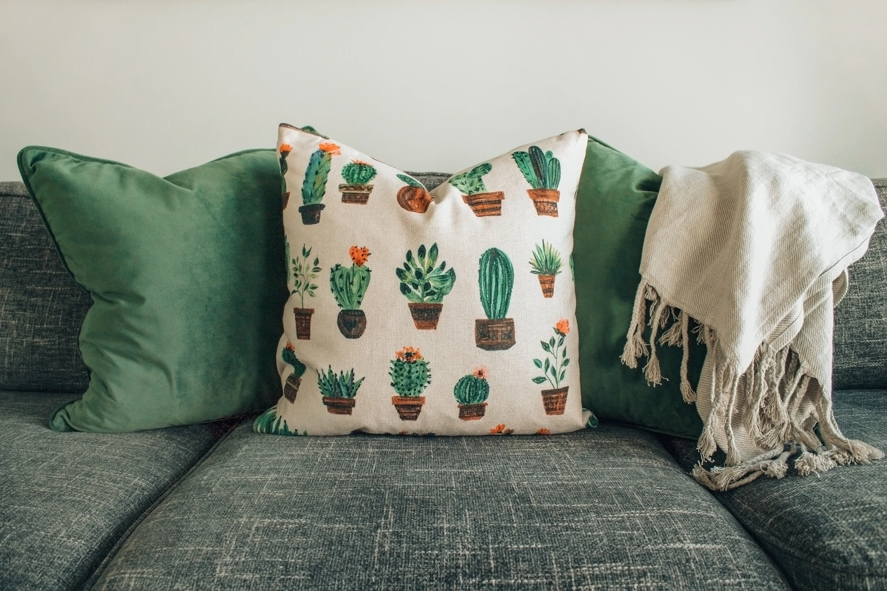 Handwoven cotton cushions and a fringed throw styled on a gray sofa