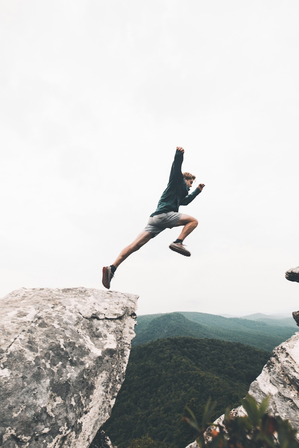 man jumping above rock mountain