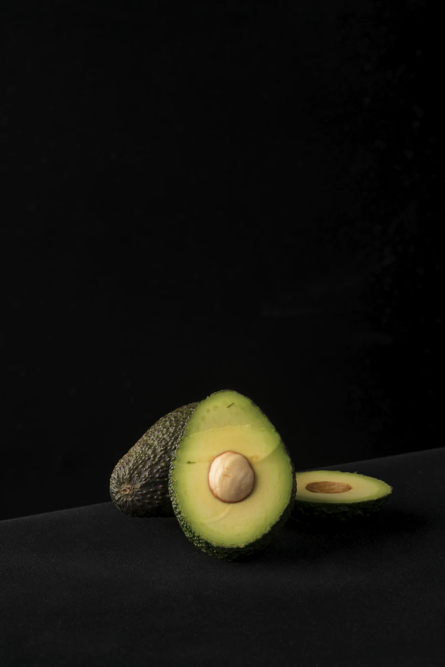 Halved avocado with the seed on a dark background