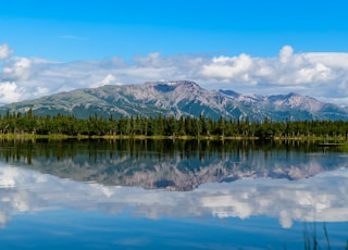 mountain and blue body of water under cloudy sky