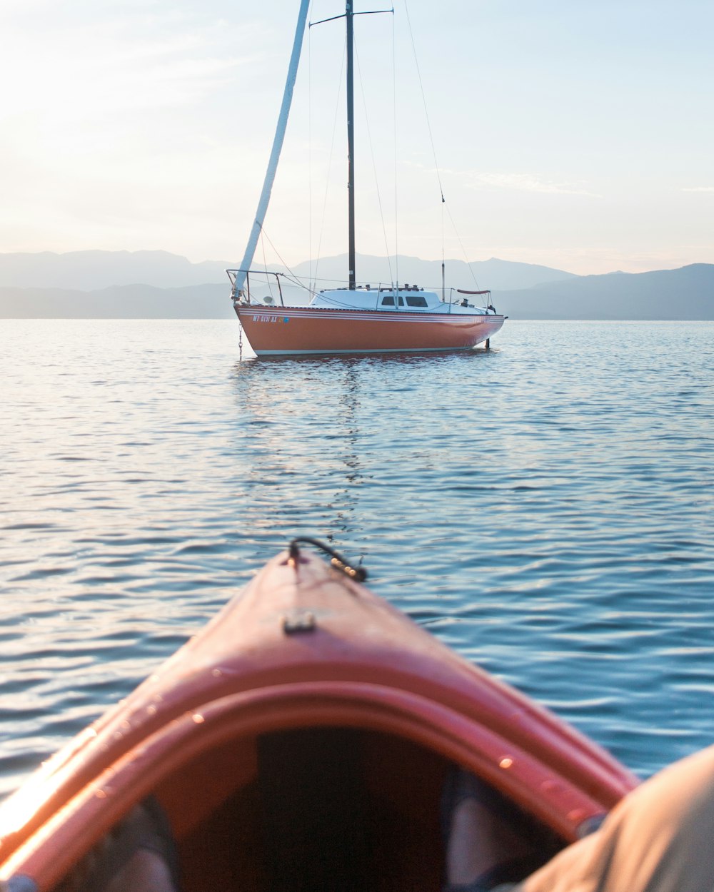 white and orange scow on body of water