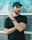 man wearing black crew-neck shirt and black cap in front of glass wall