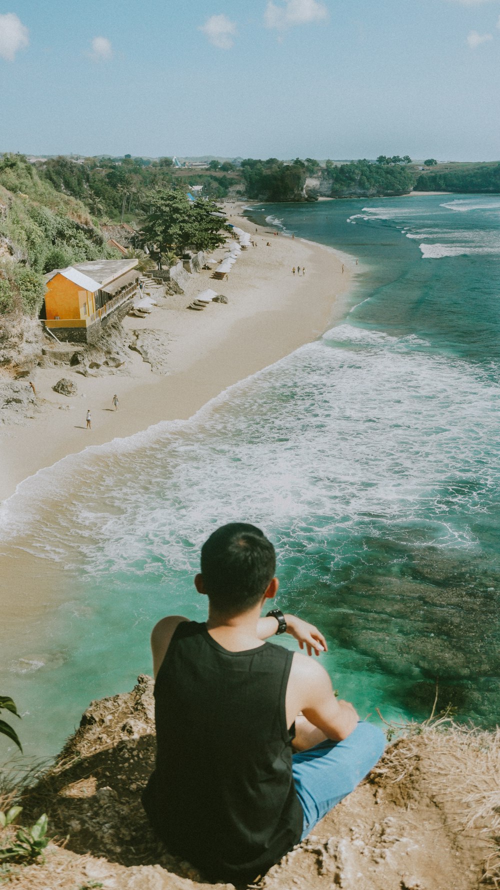 man sitting looking on body of water