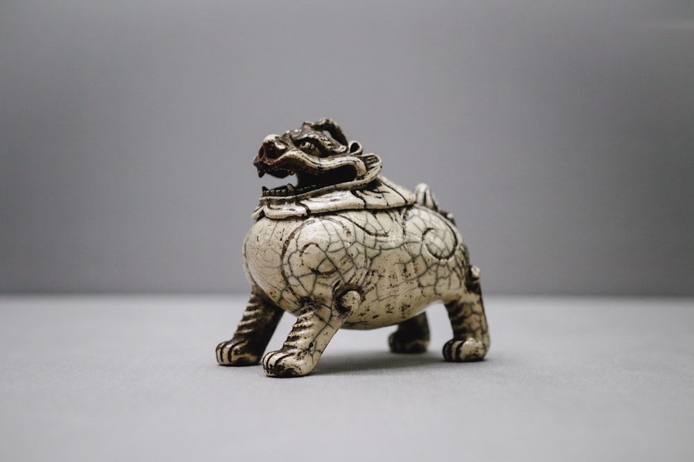 Figurina di Foo-Dog in ceramica grigia su superficie bianca