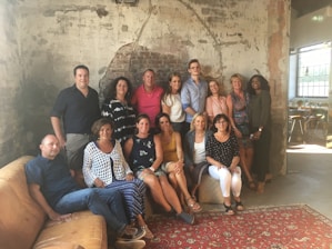 A warm, inviting photo of the Premio Verga team gathered in a cozy, book-lined room.