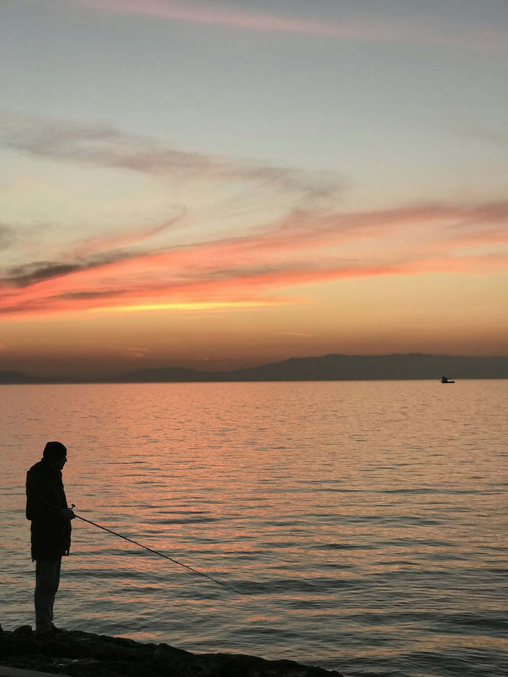 man standing on edge fishing