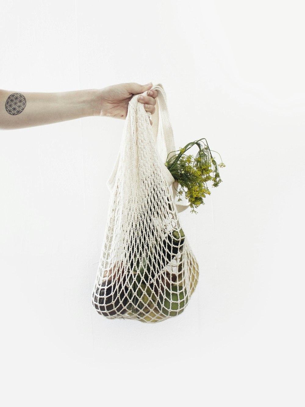 person holding white net with vegetable