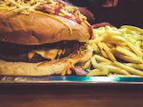 A stacked burger with crispy bacon, cheddar cheese, and a side of golden fries.